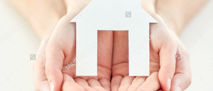 Zoomed in hands holding a paper cut out of a home.