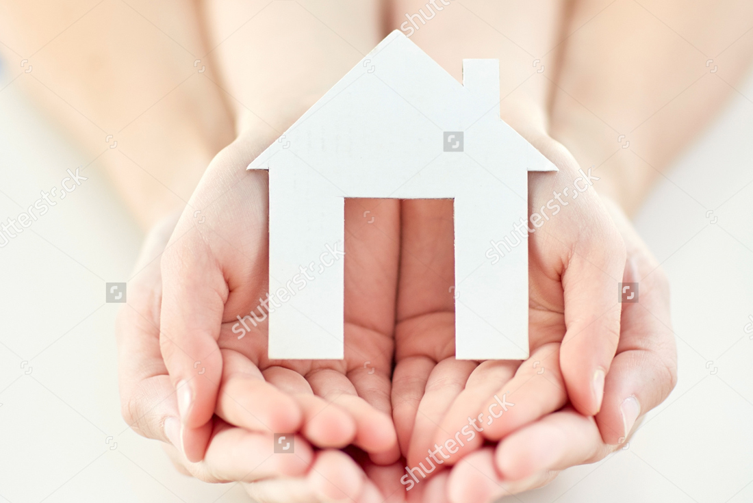 Zoomed in hands holding a paper cut out of a home.