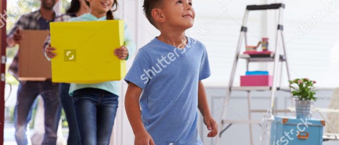 Family with children moving boxes into their new home with excitement.