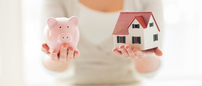 building, mortgage, investment, real estate and property concept - close up of woman holding home or house model and piggy bank