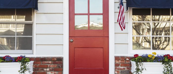 Photo of front of a home with a red door as the center focal point.