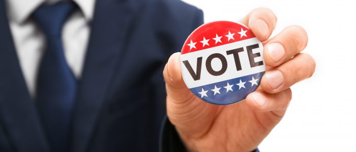 American votes concept. Man holding voting badge, close up