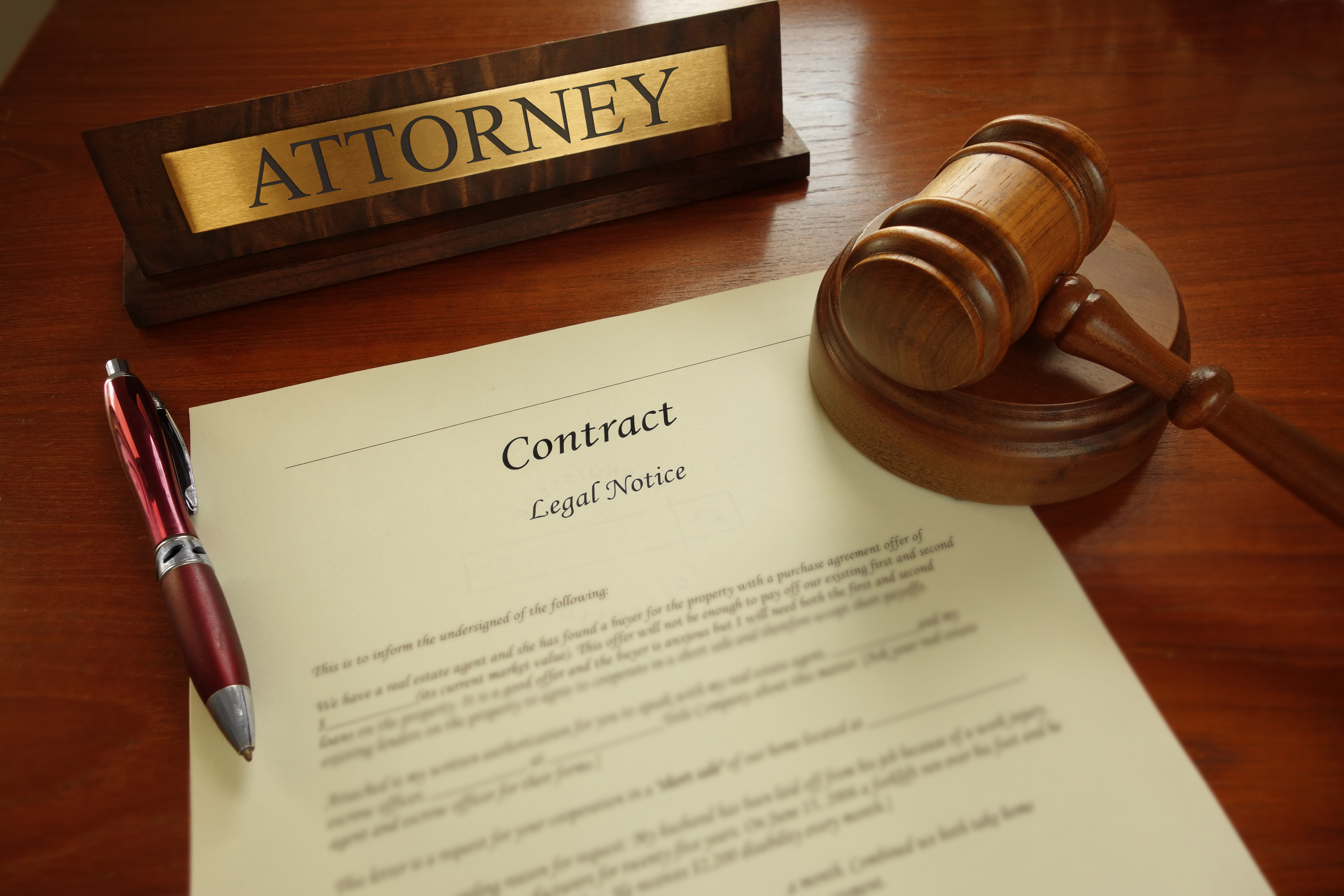 Legal contract with gavel and Attorney name plate on a desk