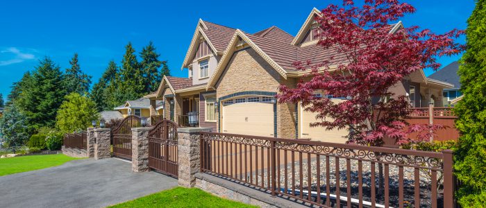 Home with gated fencing and trees turning red for the fall