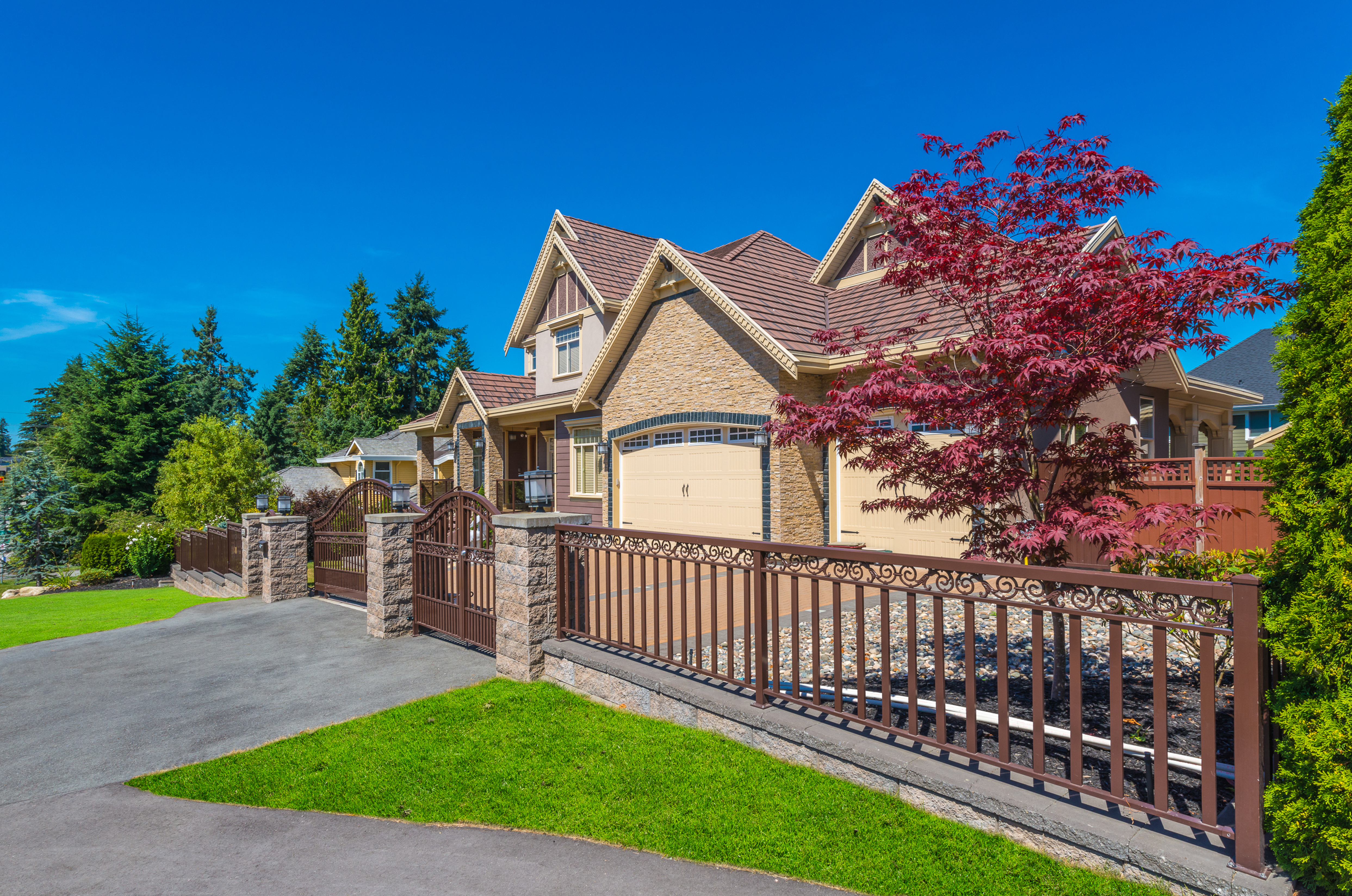 Home with gated fencing and trees turning red for the fall