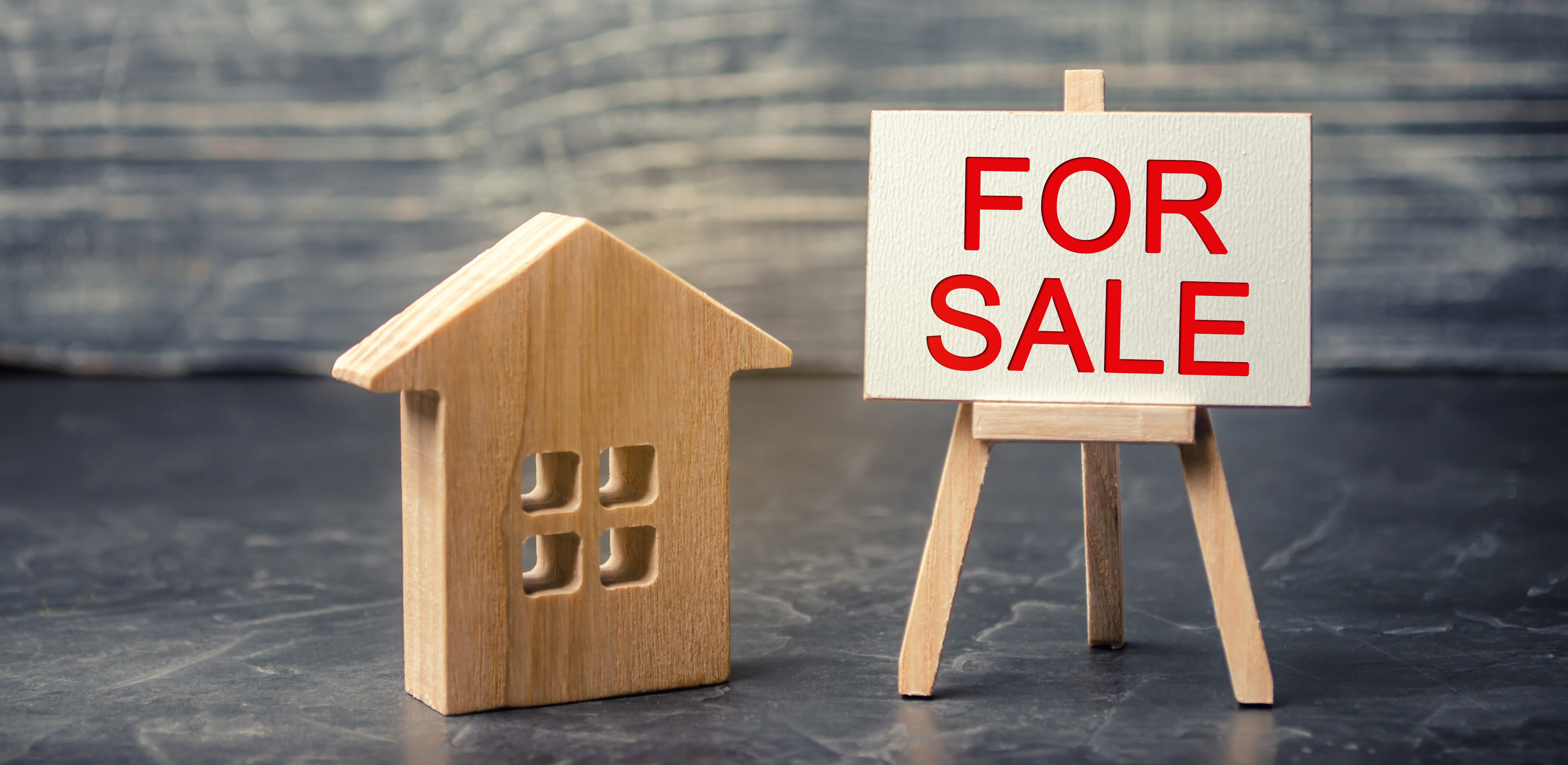 wooden house and dollars with the inscription "for sale". sale of property, home. affordable housing. sale of apartments. real estate agent services. realtor