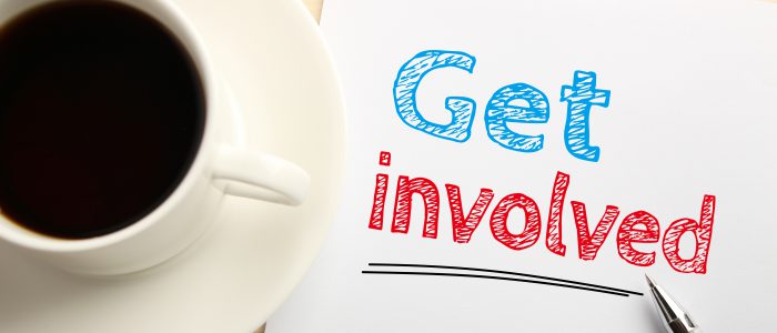 Text Get involved written on the white paper with pen and a cup of coffee aside.