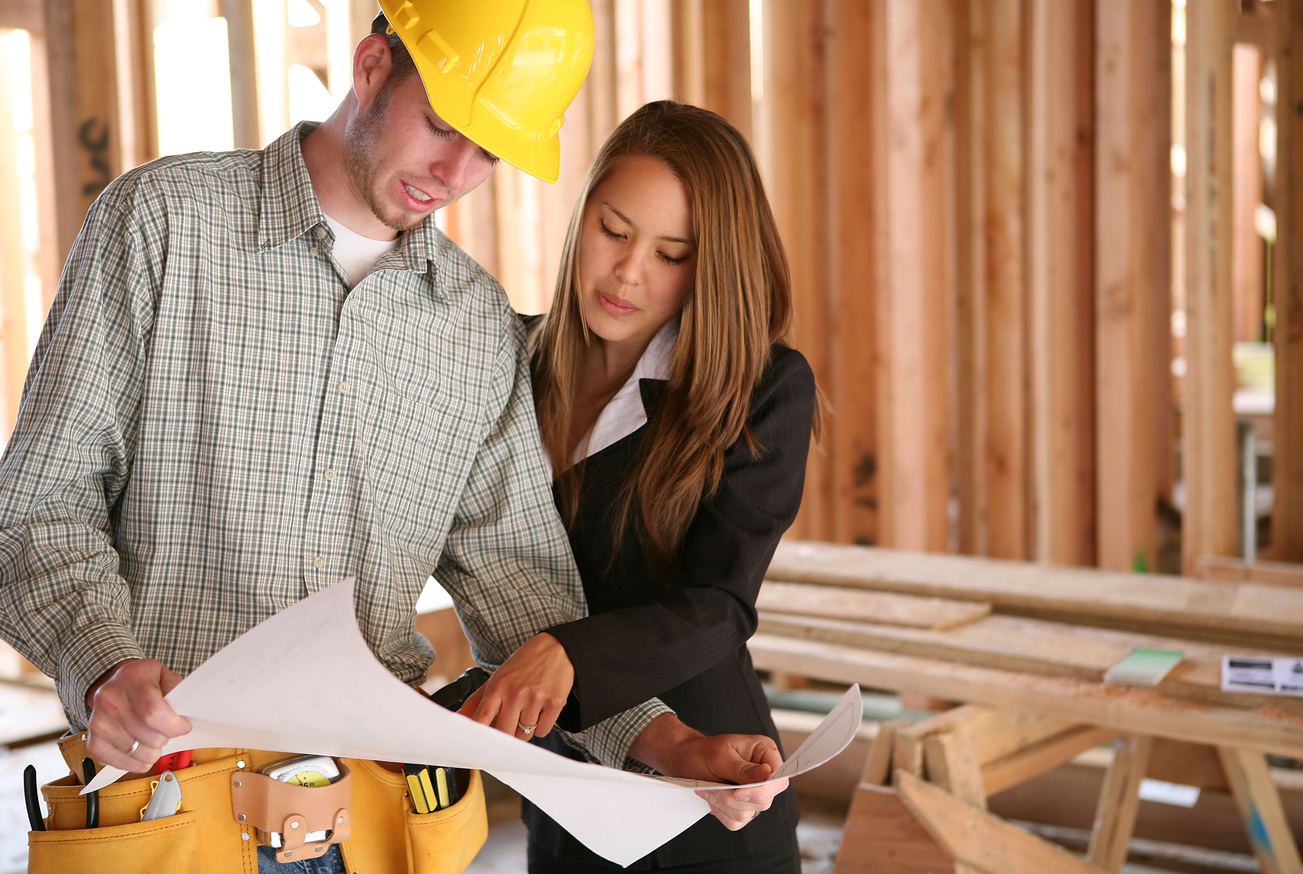 A home designer working with a home buildering and inspecting the blueprints