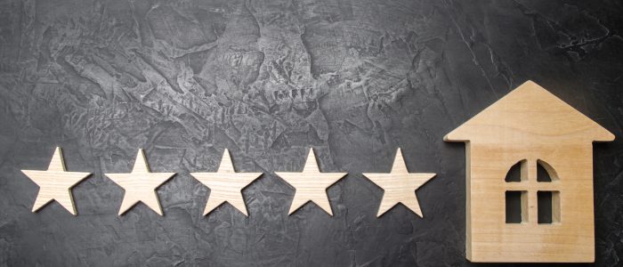 Five stars and a wooden house on a gray concrete background. The concept of the best housing, luxury apartments VIP class. The best service and universal recognition, a high score. Success.