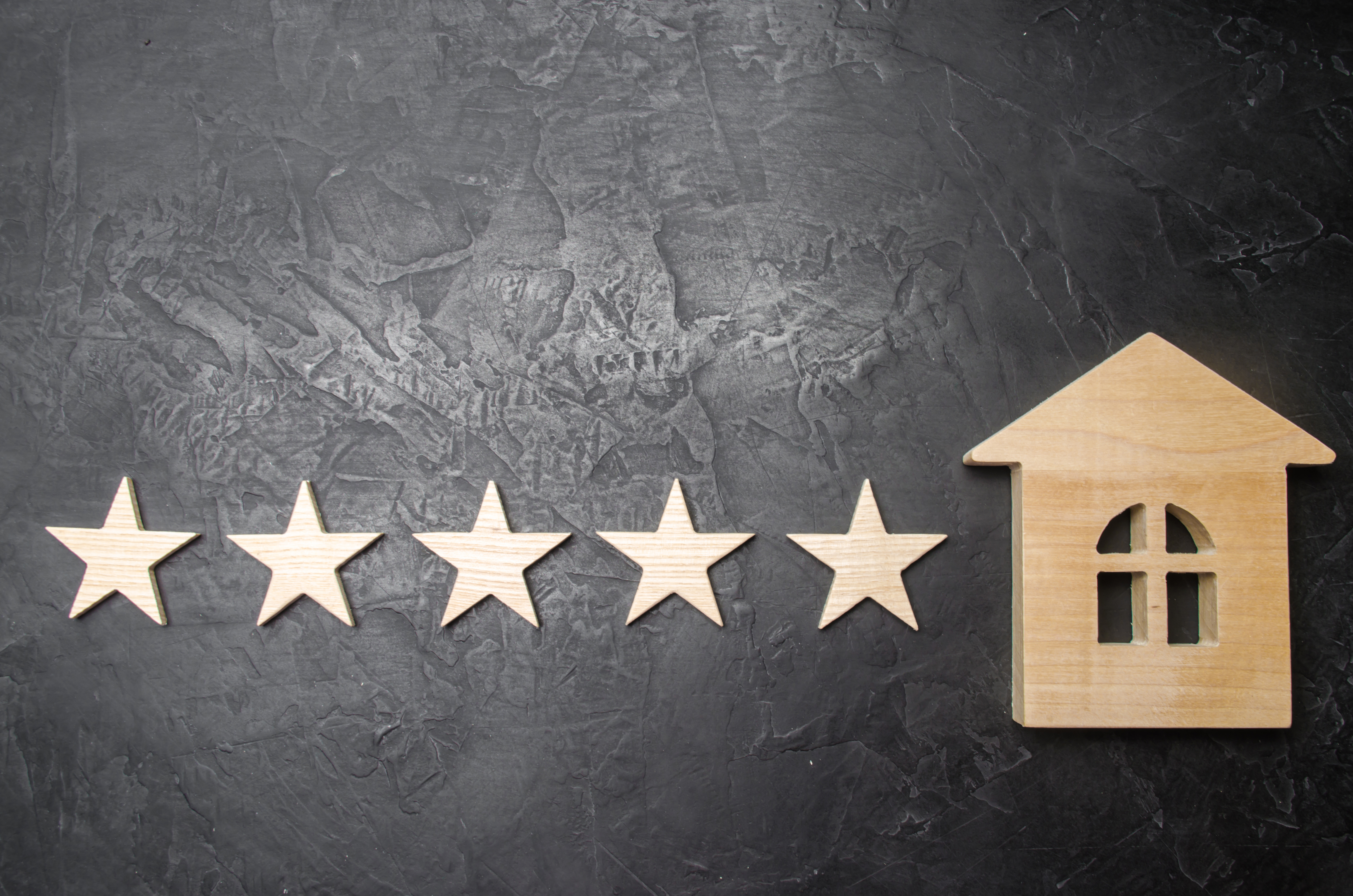 Five stars and a wooden house on a gray concrete background. The concept of the best housing, luxury apartments VIP class. The best service and universal recognition, a high score. Success.