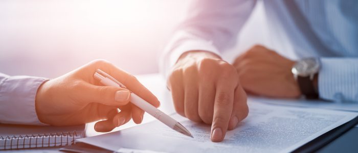 Business people negotiating a contract. Human hands working with documents at desk and signing contract.