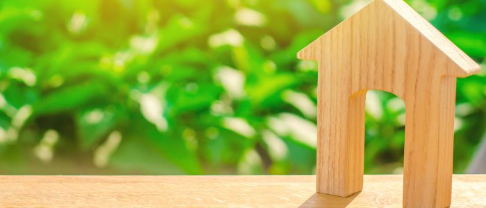Figurine of a wooden house with a large doorway on a green background . Concept of real estate, purchase and sale of housing. Affordable housing at a low price. House for the family