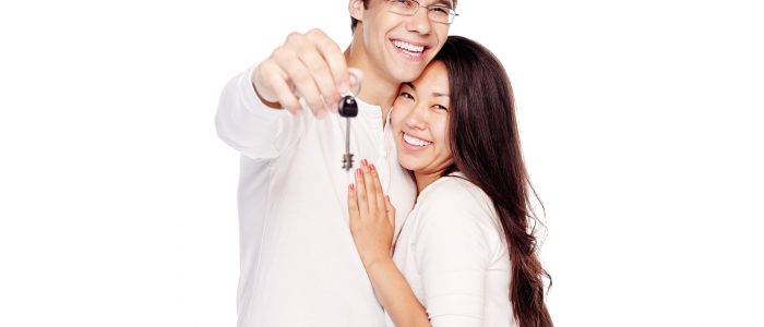 Lovely interracial couple, hispanic man and asian girl, showing key of their new house, hugging and smiling isolated on white background - real estate for young family concept