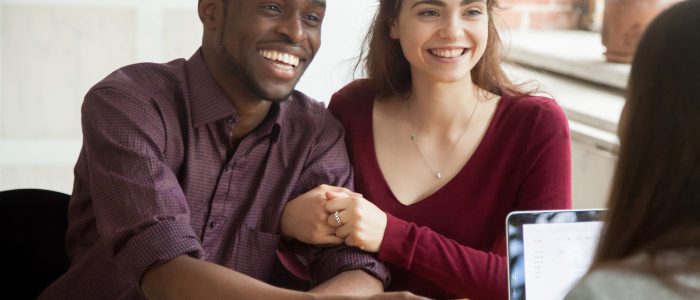 Smiling multiracial couple customers shaking hands with mortgage broker or financial advisor, happy attractive black and white family handshaking lawyer bank worker taking loan, making purchase deal