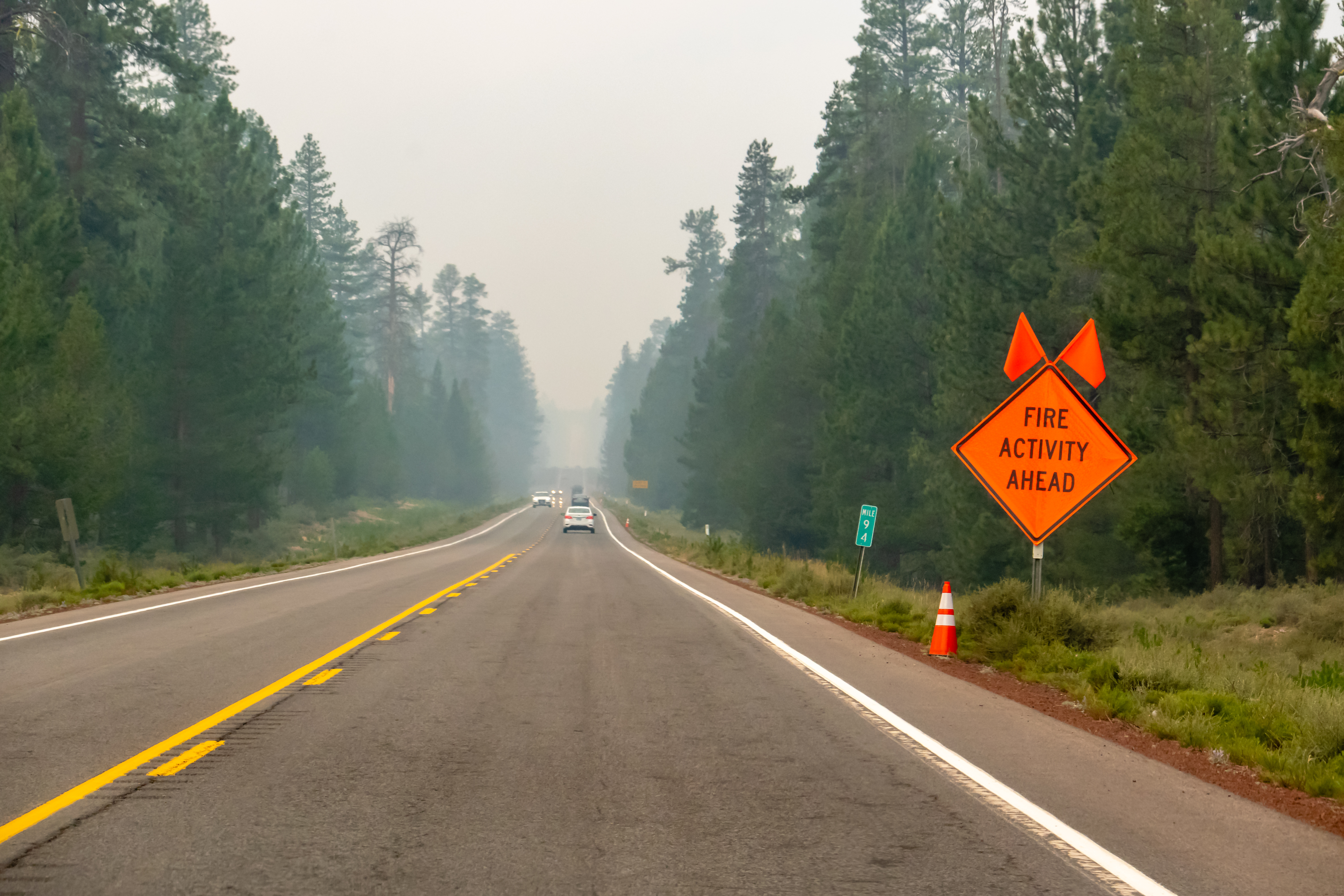 Wildfire smoke filled highway in Southern Oregon, sign at roadside "FIRE ACTIVITY AHEAD".