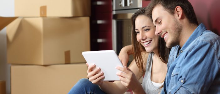 Couple sitting on the floor of the kitchen and buying online with a tablet and moving home