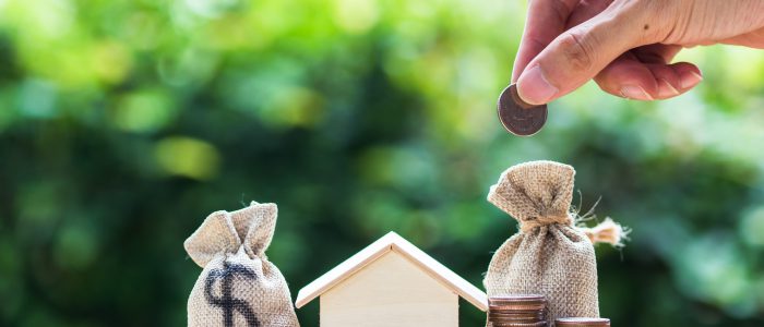 Saving money, home loan, mortgage, a property investment for future concept : A man hand putting money coin over small residence house and money bag